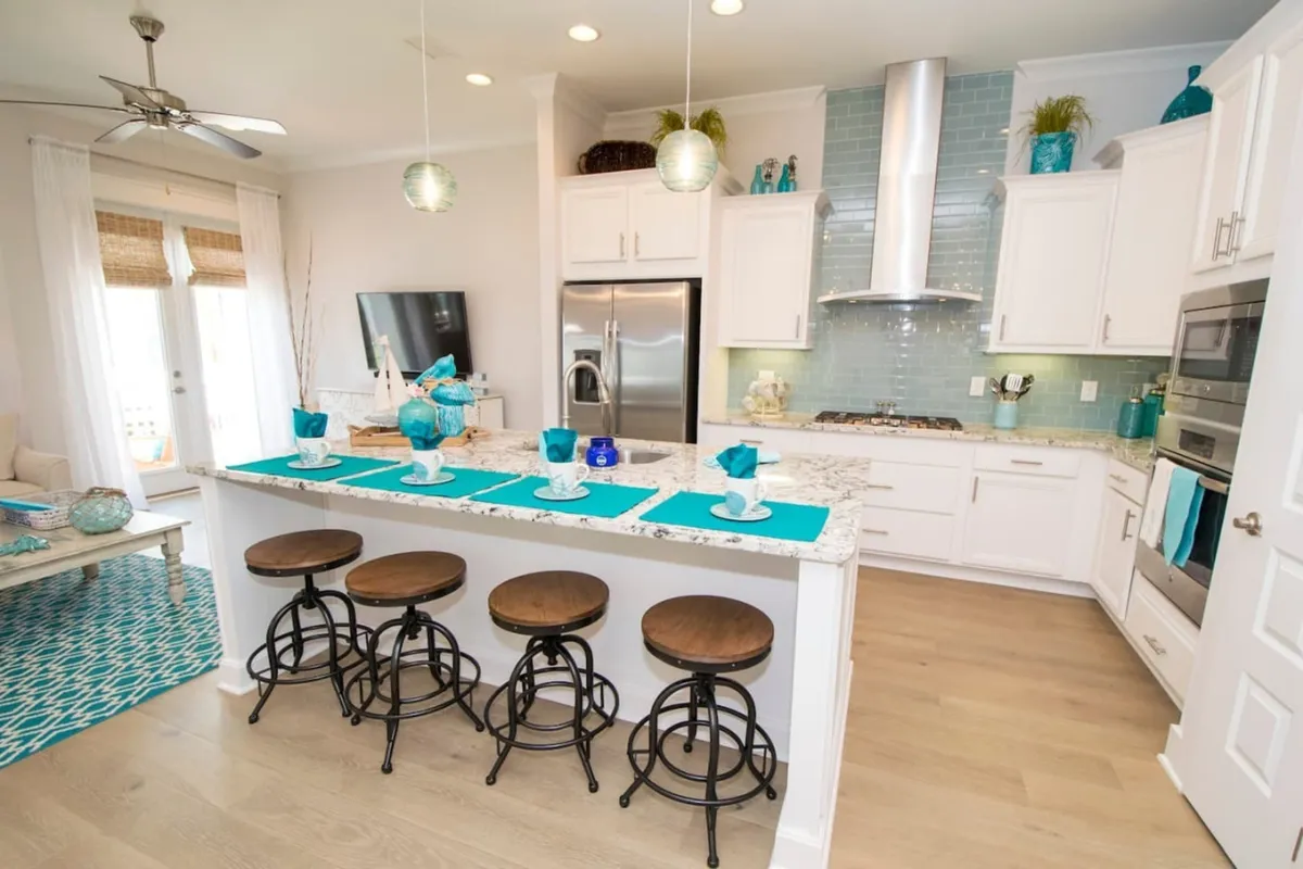 A vibrant kitchen scene with a spacious island, bar stools, modern appliances, and colorful decor. The layout invites entertaining and casual gatherings, with ample counter space for preparing meals or enjoying a cup of coffee. The overall atmosphere is lively and welcoming, ideal for socializing.