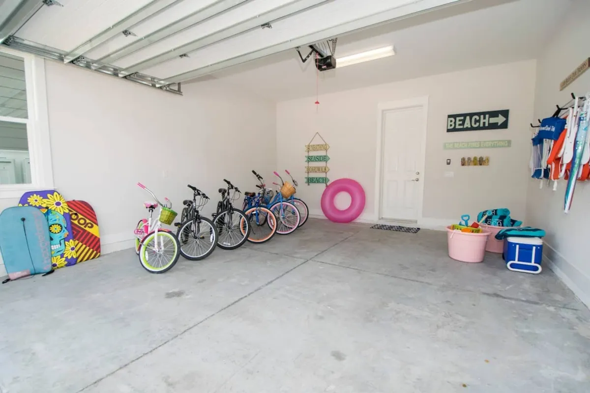 This image shows a row of bicycles, a pink inflatable swim ring, and an assortment of beach gear such as boogie boards and coolers, all organized in a bright interior space with beach-themed wall decor. The scene radiates energy and anticipation for beach adventures.